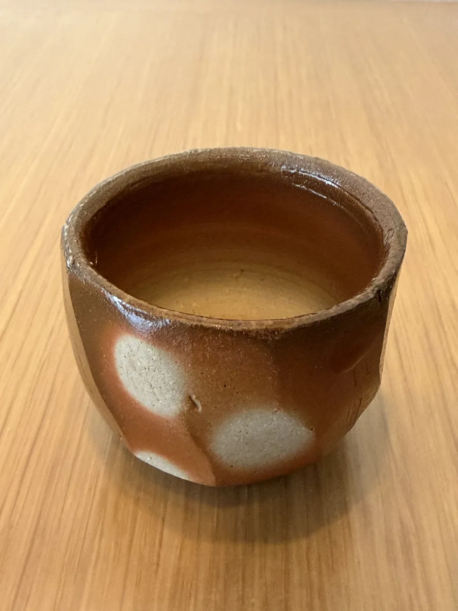 Sake in the Bizen guinomi seen at an angle, with the brown interior showing through