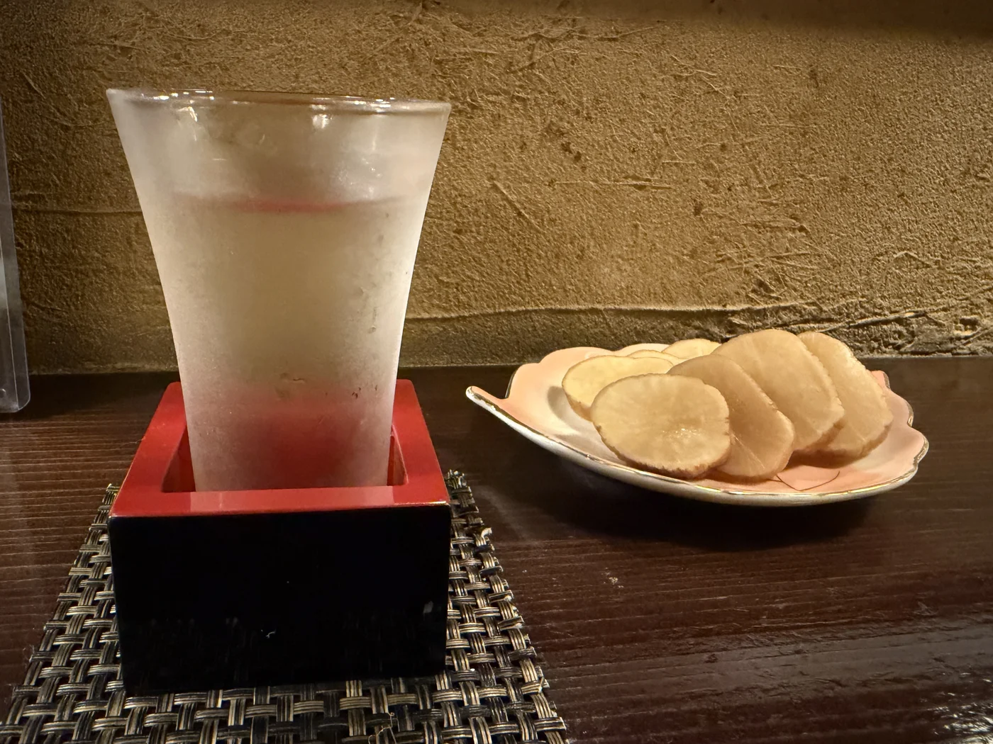 A glass of Senkin Senko-Hanabi with smoked pickled daikon iburigakko