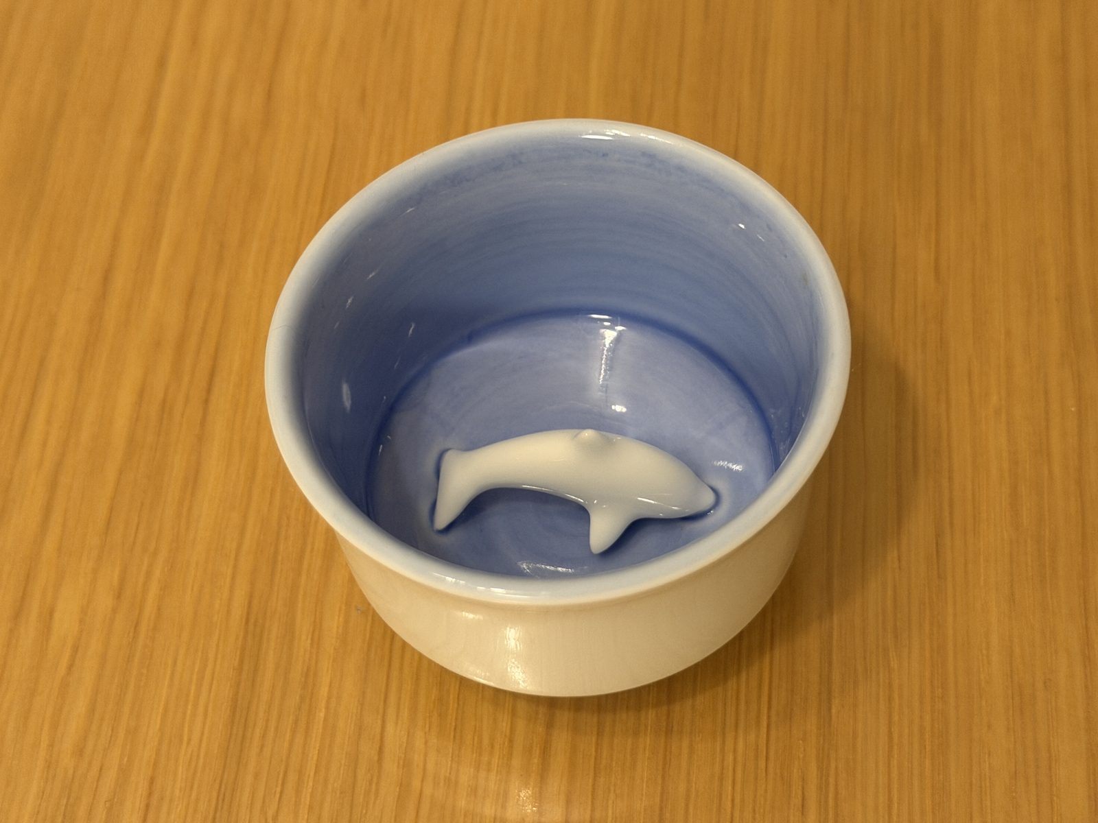 Empty Takahama Ware guinomi showing the blue interior and dolphin