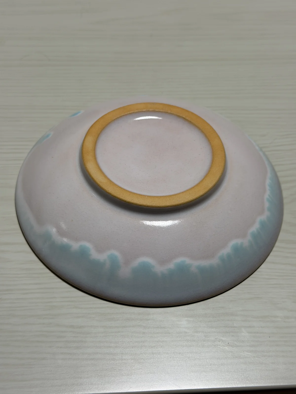 Reverse of the Hagi ware plate with a pinkish-white glaze, pale blue glaze runs, and an unglazed foot ring