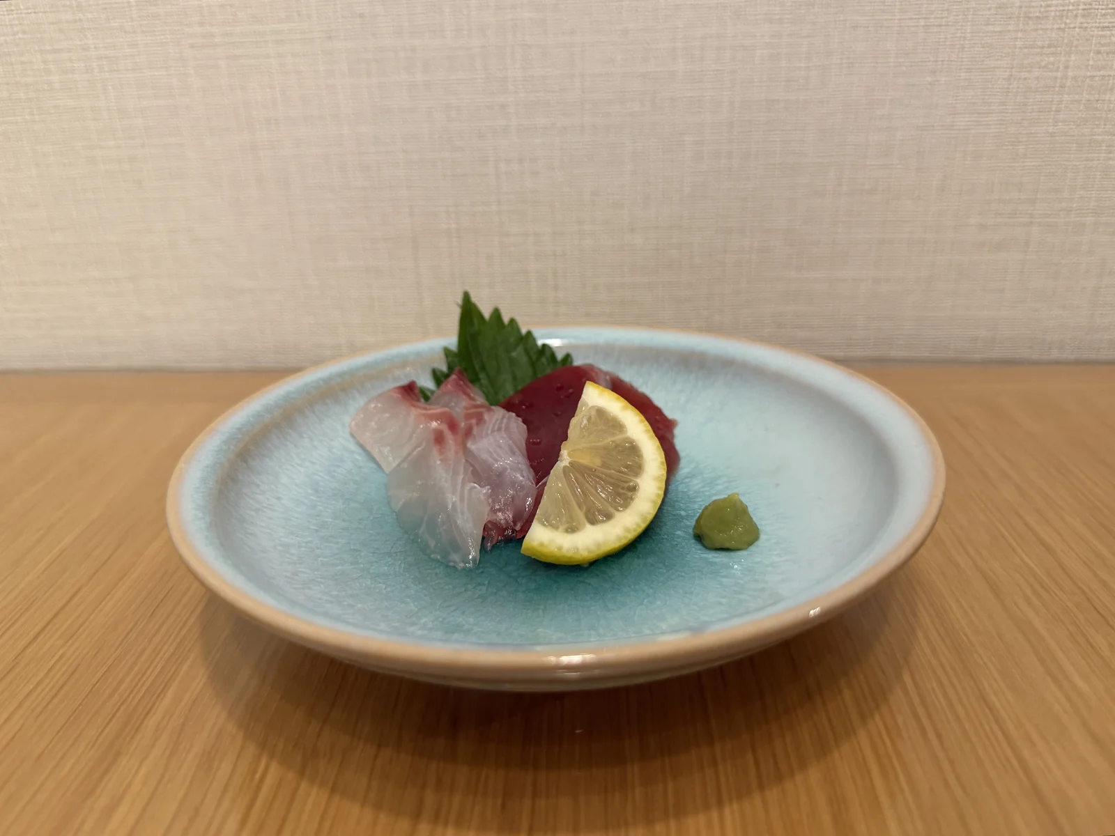 Sashimi with lemon, a shiso leaf, and wasabi on the pale blue Hagi ware plate